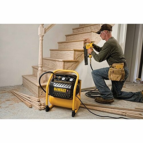 Carpenter using a nail gun on wooden stairs with compressor